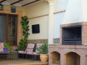 patio al aire libre con chimenea y TV en CASA RURAL LOS POCICOS, en San Carlos del Valle