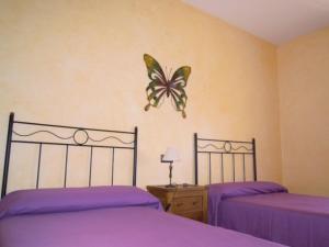 a bedroom with two beds and a butterfly on the wall at CASA RURAL LOS POCICOS in San Carlos del Valle +49 photos