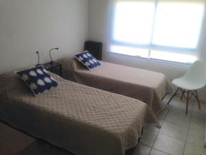 Habitación con 2 camas, silla y ventana en LAS MARINAS RENT en Bahía Blanca