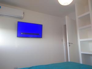 TV de pantalla plana colgada en la pared de un dormitorio en COZY II DEPARTAMENTO EN PLENO CENTRO DE MENDOZA en Mendoza