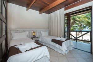 a hotel room with two beds and a balcony at Pousada Recanto do Lobo in Porto De Galinhas