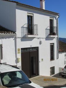 una casa blanca con garaje y un coche aparcado delante en CALLE CALVARIO 10 en Zufre