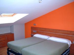 - une chambre dotée d'un lit avec un mur orange dans l'établissement Pardiola Baserria, à Hernani