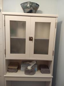 a white cabinet with towels in a bathroom at Pokai Bay Penthouse Studio in Waianae