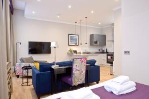 a living room with a blue couch and a kitchen at Destiny Scotland Charlotte Square Apartments in Edinburgh