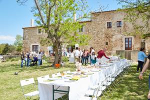 einen langen Tisch mit weißen Stühlen und Menschen vor einem Gebäude in der Unterkunft Can LLorens in Llagostera