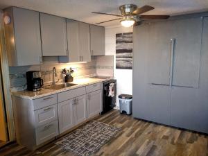 a kitchen with white cabinets and a sink and a refrigerator at Pokai Bay Penthouse Studio in Waianae