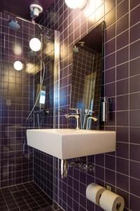 een badkamer met een wastafel, een spiegel en paarse tegels bij Holmen Lofoten in Sørvågen