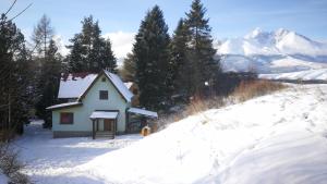 een klein huis in de sneeuw met bergen op de achtergrond bij Chata Eliška in Stará Lesná