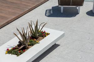a white bench with plants and flowers on a sidewalk at 360ᵒ Luxury View Collection - Adults Only in Limenaria