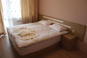 Schlafzimmer mit einem Bett mit weißer Bettwäsche und Kissen in der Unterkunft Къща за гости Мишурови in Smoljan