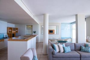 a living room with a couch and a kitchen at Bay Reflections Camps Bay Luxury Serviced Apartments in Cape Town