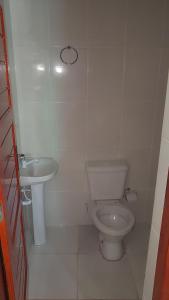 a white bathroom with a toilet and a sink at APARTAMENTO DO OTTO in Oliveira Fortes