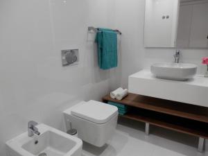 un bagno bianco con un water e un lavandino di Ripple - Modern Condo with pool, aircon, parking a Lisbona Altre 10 foto