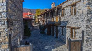 un callejón entre 2 edificios de piedra con balcón en Nostos, en Palaios Agios Athanasios