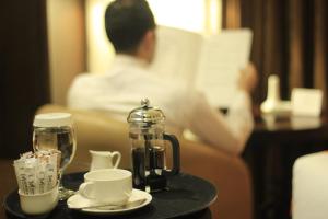 a person reading a book in a hotel room with a coffee maker on a table at Meneur Hotel in Amman