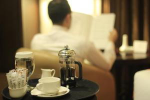 una persona leyendo un libro en una habitación de hotel con una cafetera en una mesa en Meneur Hotel, en Amán