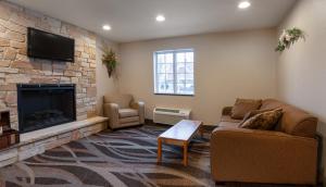Cobblestone Inn & Suites - Durand في Durand: غرفة معيشة مع أريكة ومدفأة