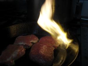 eine Bratpfanne mit zwei brennenden Fleischstücken in der Unterkunft Solhof-Schömberg in Loßburg