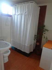 a bathroom with a white shower curtain and a toilet at Cabañas Krava Inn in Hanga Roa