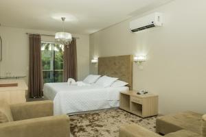 a bedroom with a white bed and a living room at Marruá Hotel in Bonito