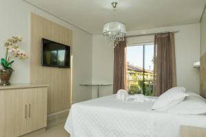 a bedroom with a white bed and a window at Marruá Hotel in Bonito