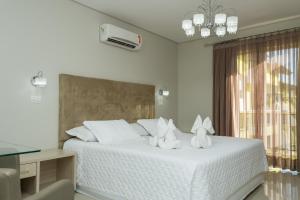 a bedroom with a white bed with two stuffed animals on it at Marruá Hotel in Bonito