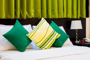 Una cama con almohadas verdes y amarillas. en Hotel Fatima Inn, en Tarapoto