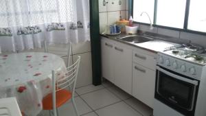 Una cocina con una mesa, una estufa y un fregadero. en Pousada do Nico, en São Gabriel