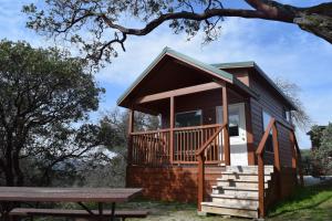 a tiny house with a porch and a bench at Yosemite RV Resort in Coarsegold