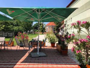 a patio with a table and a green umbrella at PENZION ANIKO GOLD *** in Horné Saliby