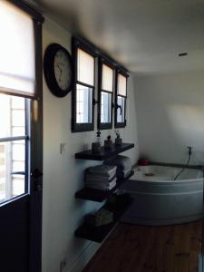 a bathroom with a tub and a clock on the wall at Villa Camélia in Bayeux