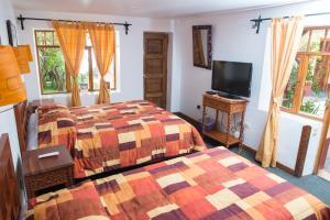 a bedroom with two beds and a flat screen tv at Hosteria de Anita in Cusco