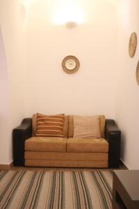a couch in a living room with a clock on the wall at Casa Centro Histórico Beja - Castelo in Beja