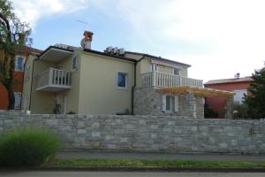 una casa con una pared de retención y una valla en Apartments Villa Ela, en Umag