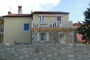 a house with a balcony on top of a stone wall at Apartments Villa Ela in Umag