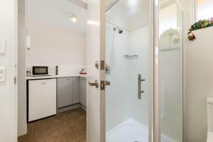 baño con ducha y puerta de cristal en Alpine Motel en Wanaka