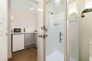 baño con ducha y puerta de cristal en Alpine Motel, en Wanaka