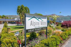 un cartel para un motel alpino en un jardín en Alpine Motel, en Wanaka