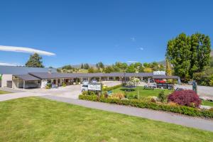 a building with a park in front of it at Alpine Motel in Wanaka