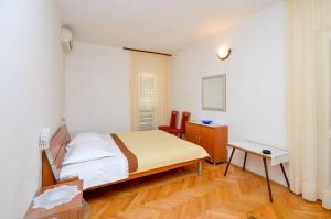 a small bedroom with a bed and a table at Apartment and Rooms Biserka in Novalja
