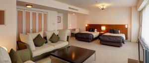 une chambre d'hôtel avec un canapé et deux lits dans l'établissement Kagetsuen, à Hakone