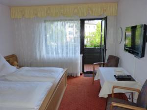 a hotel room with two beds and a table and a television at Cafe-Pension Waldesruh in Willingen