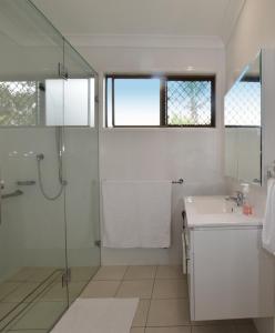 a white bathroom with a shower and a sink at Holiday House in Brisbane