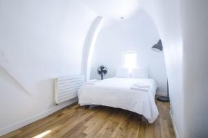 a white bedroom with a white bed and wooden floors at Dreamyflat - Penthouse Opera in Paris