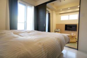 1 dormitorio con 1 cama blanca grande y espejo en momo premium 403, en Sapporo