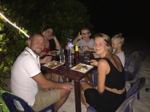 a group of people sitting around a table with food at Noomuraka Inn in Omadhoo