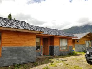 a house in the mountains with a car parked in front at Aysen Bike Cabañas in Puerto Aisén
