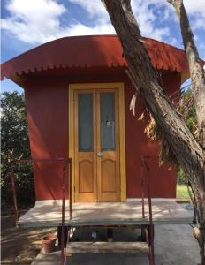 a small red building with a door and a tree at Glamping Gypsy Hobart in Richmond