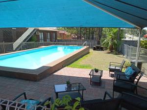 une grande piscine entourée d'un parasol bleu. dans l'établissement Molly Morgan Motor Inn, à Maitland